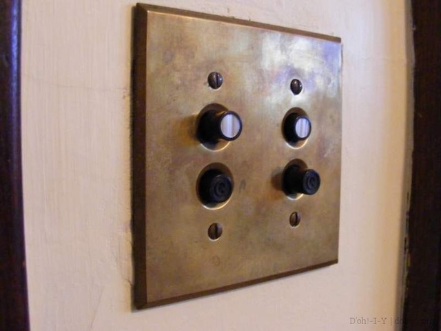 Side view of a push-button light switch installed on a wall, highlighting the simplicity and elegance of its design against the backdrop of a painted wall