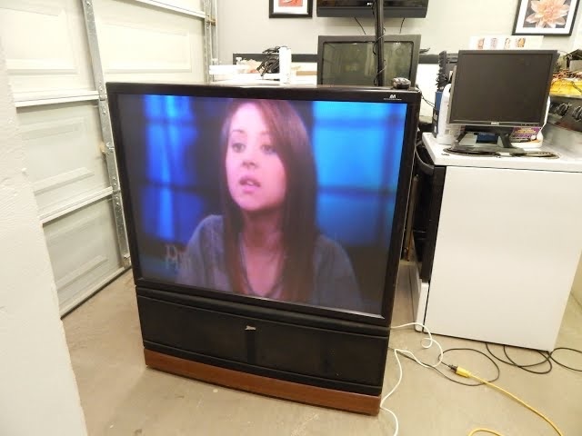 An iconic rear-projection TV still holding its place in a home garage, proving how durable and reliable these devices were