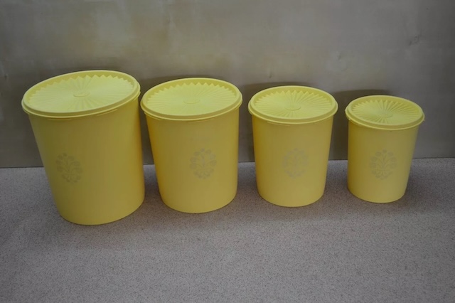 A set of vintage Tupperware containers, neatly lined up in sizes, showcasing their practicality and timeless design that made them a must-have item in kitchens for decades