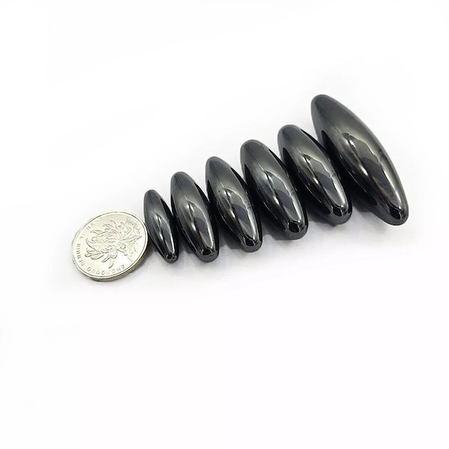 Different sizes of the oval magnets placed beside a coin for size comparison and perspective