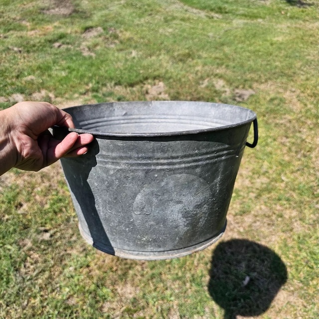 The practical handle of the vintage washtub, still strong, evokes the hard work and resilience of past generations