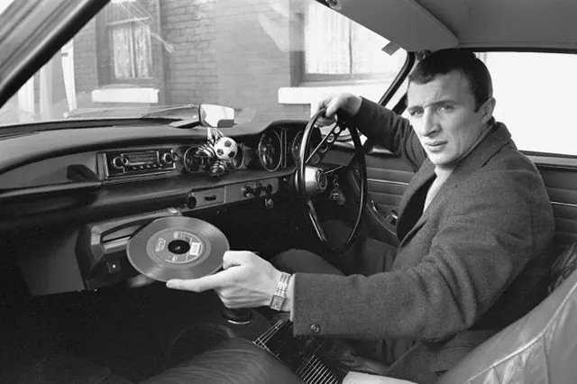 Mike Summerbee shows the record player in his Volvo P1800, 1976