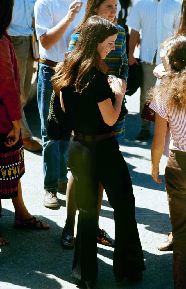 A high school student confidently stood among classmates, proudly showing off her black bell-bottoms that became a signature of the era's fashion.