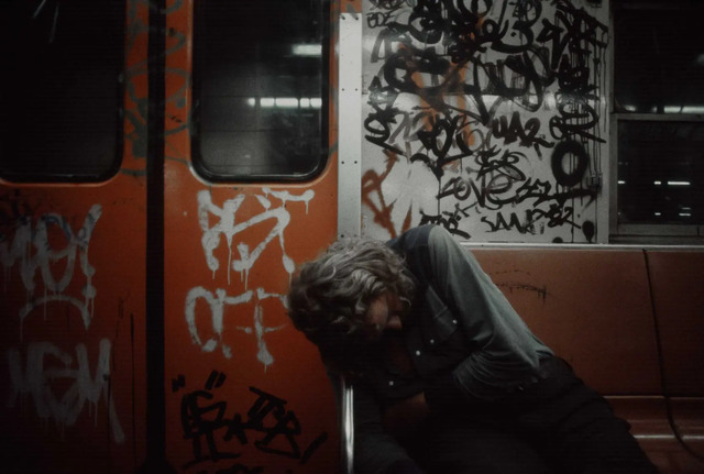 A man drifts off to sleep in the chaos of a crowded subway car, capturing the exhaustion and resilience of daily commuters.