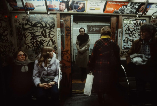 A man, on the verge of boarding a subway car, stands at the threshold of the city’s lifeblood, ready to dive back into New York's vibrant pulse.