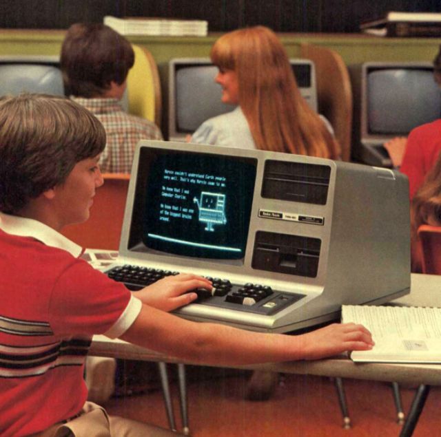 Students using early home computers in a classroom setting, emphasizing how personal computing was making its way into education in the 1980s.