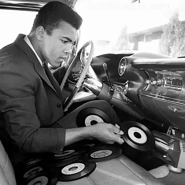 A glimpse of Muhammad Ali enjoying his Philips record player in the luxurious interior of his 1959 Cadillac Eldorado.