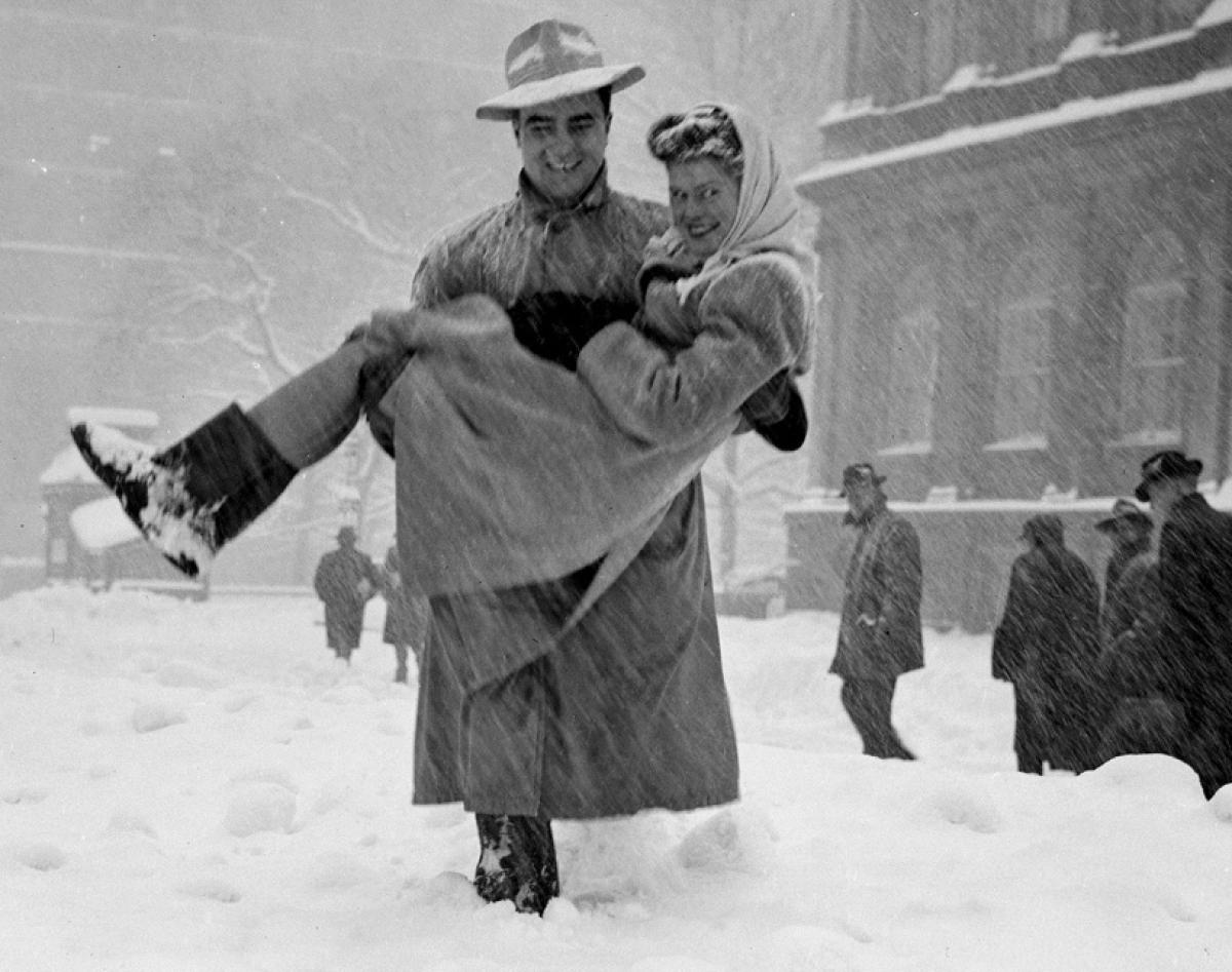 A woman hitches a ride with a kind stranger outside City Hall, while others trudge through the snowy streets, 1947