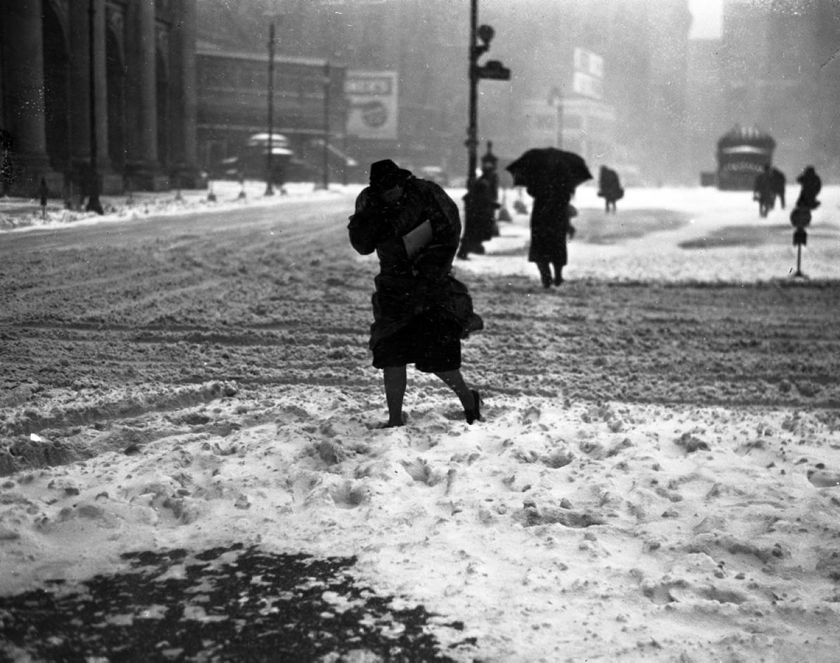 Braving the icy streets, pedestrians hurry home through the snow-covered city, 1940.