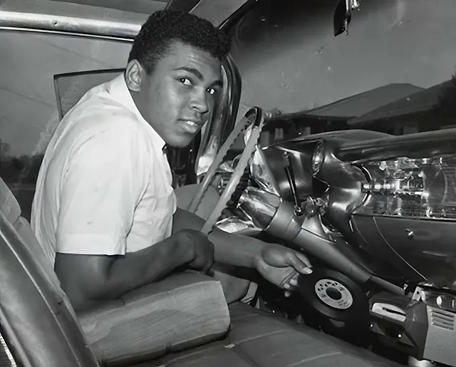 Muhammad Ali behind the wheel of his stylish 1959 Cadillac Eldorado, embodying both class and charisma.