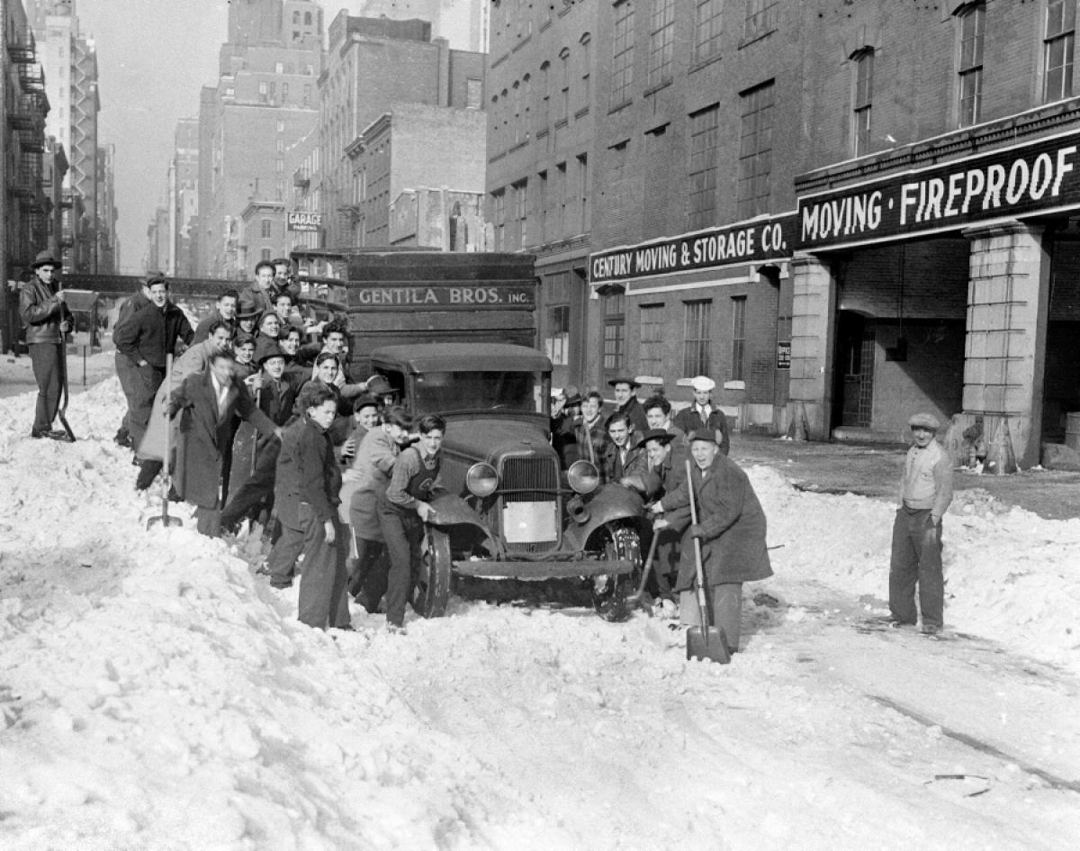 Teamwork is key as drivers struggle to free a car lodged in nearly seven inches of snow on East 38th Street, 1943.