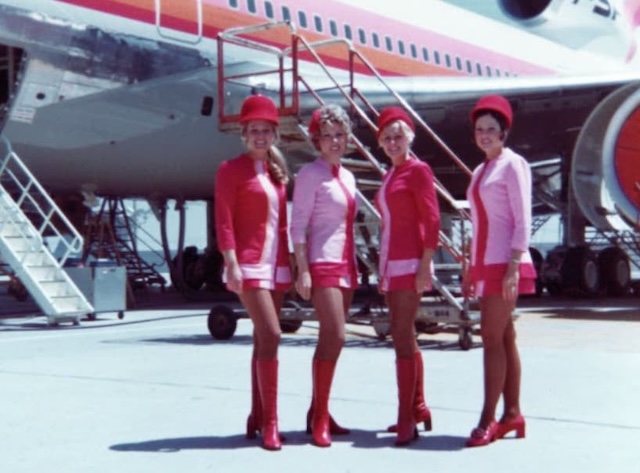 Four flight attendants pose together, smiling for the camera. Their cheerful expressions capture the moment