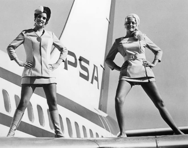 Two stewardesses smile while posing on the wing of a PSA plane