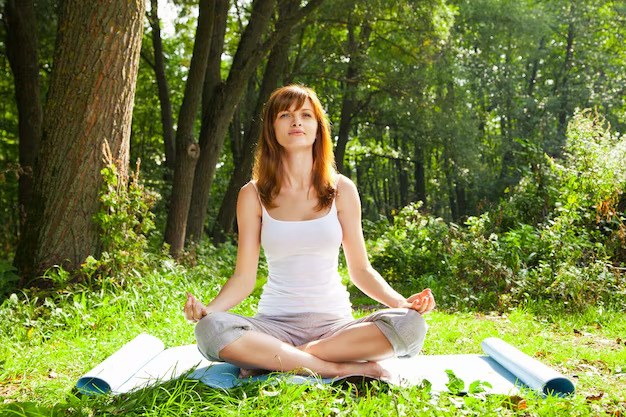 Practicing mindful breathing in a calm natural setting enhances relaxation and stress relief.
