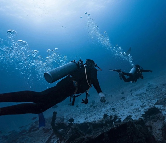 Scuba divers exploring the depths of the Great Blue Hole, unveiling its mystery and beauty beneath the surface.