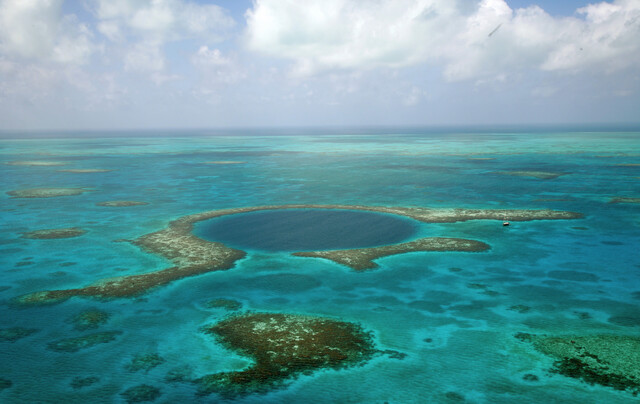 The stunning aerial view of the Great Blue Hole, showcasing its massive size in the Belizean waters.