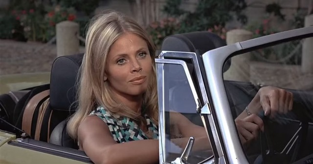 Britt Ekland, captured in a candid shot behind the wheel, showcasing her timeless charm and style.