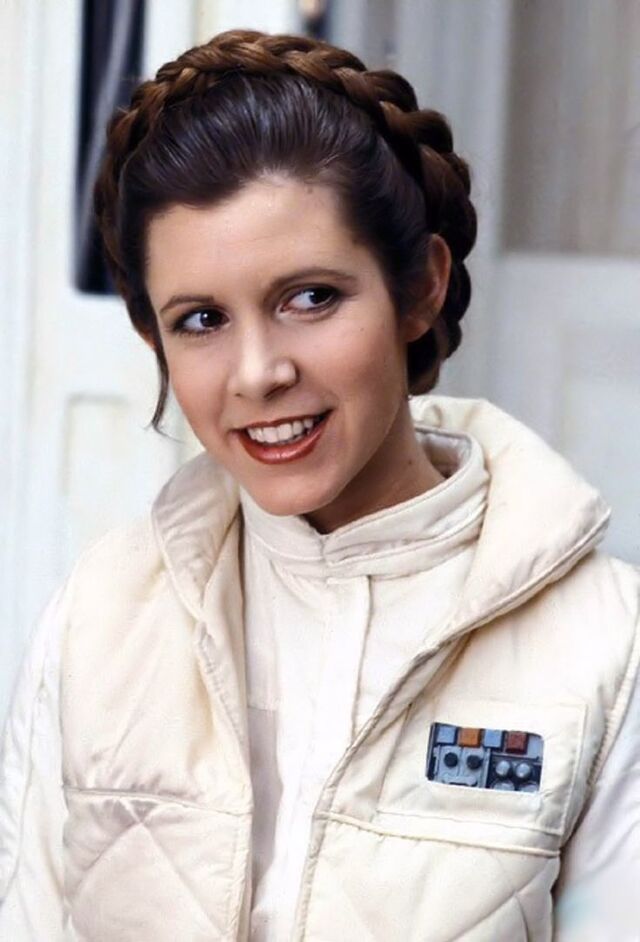 Carrie Fisher in the iconic Princess Leia braids, a timeless look that became a hallmark of her character in Star Wars.