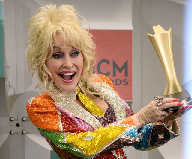 Dolly Parton with her signature joyful smile, proudly holding an award at the ACM Awards, celebrating her unmatched contributions to country music.