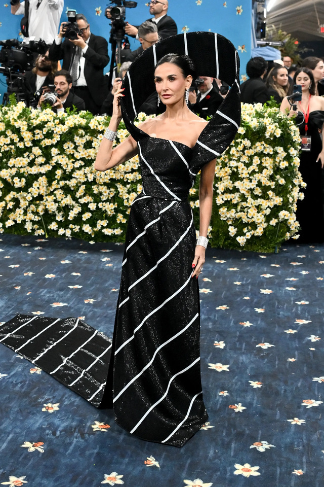 The metallic black-and-white stripes, oversized puff sleeves, and intricate headpiece symbolizing the tie’s knot added drama and depth to the look.