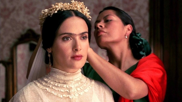 Hayek famously adopted Kahlo’s signature unibrow, traditional Tehuana dresses, and bold accessories—not as a costume, but as a defiant statement of identity.